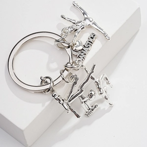 Detailed view of silver metal keychain featuring gymnast pendants and engraved plate