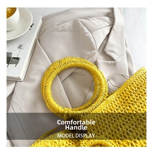 Detail of hand-woven yellow straw bag featuring round handles and decorative beads