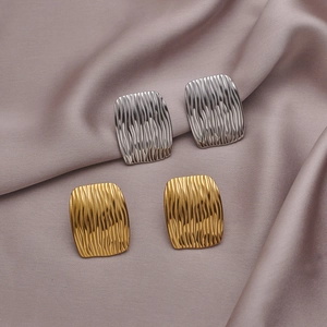 Detail of gold and silver bow-shaped stud earrings with textured metallic finish
