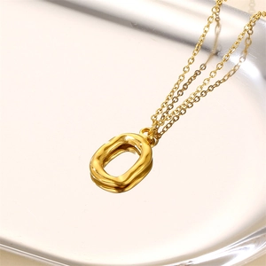 Chic golden necklace with irregular oval pendant displayed on reflective silver tray