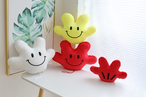 Detail of Mickey-style plush hand pillows in red, yellow, and white on a white desk