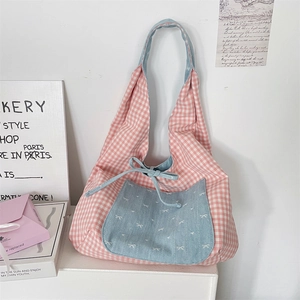 Detail of pink plaid tote bag featuring a blue denim front pocket and cute ribbon bow