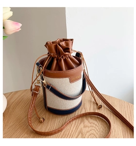Detail of canvas bucket bag with brown leather drawstring and gold metal hardware