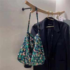 Detailed close-up of floral canvas tote bag hanging on wooden hanger in a natural setting