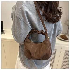 Detail of a dark brown ruched dumpling bag featuring cloud-shaped handle and metal zipper