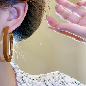 Detail view of a model wearing a gold velvet flocked round earring in retro style