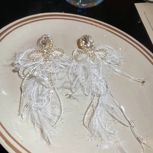 Detail view of crystal bow knot earrings with white feather tassels on a plate