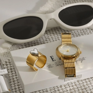 Detailed view of luxury gold heart ring and matching metal watch set on a textured surface