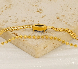 Detail of double-layer gold chain bracelet with blue marquise zircon on stone texture