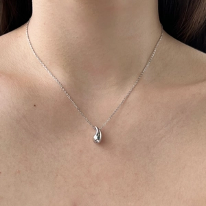 Close-up of minimalist silver water drop pendant necklace on model neck with slender chain