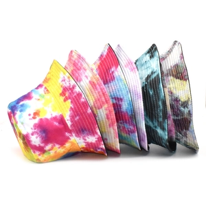 Vue détaillée montrant divers motifs tie-dye colorés sur des bobs réversibles en coton