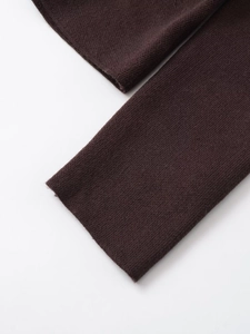 Détail du poignet d'un blazer en maille café montrant la texture fine et la couture