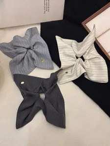 Close-up of striped bow hair scrunchies with vintage metal buttons on fabric surface