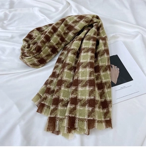 Close-up of thick winter houndstooth scarf with tassels in green and brown tones