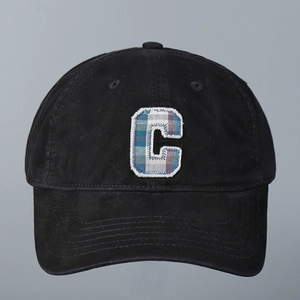 Close-up of black cotton baseball cap with plaid embroidered letter C and frayed edges