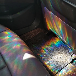 Rainbow prism suncatcher film creates colorful light patterns on car interior seats