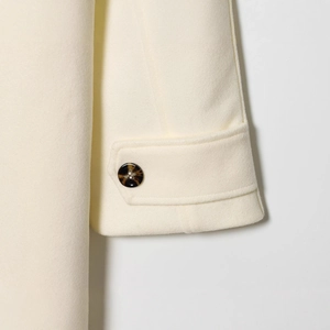 Close-up of creamy double-sided wool coat sleeve featuring premium amber button detailing