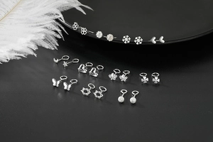 Macro shot of silver stud earrings collection with clover and star shapes on white feathers