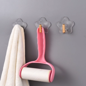 Drei Klebehaken in Sternform an der Wand mit Handtuch und Fusselroller