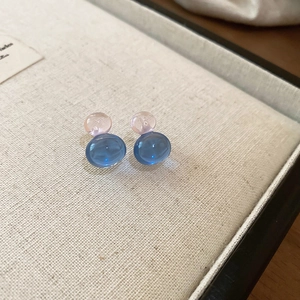 Macro detail of ice-clear gourd earrings in sky blue and pale pink glass finish