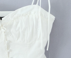 Detail of white lace embroidery camisole with ruffles and buttons on cotton fabric