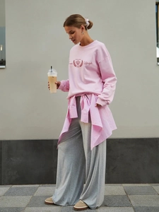 Completo casual da donna con felpa rosa oversize e pantaloni grigi a gamba larga