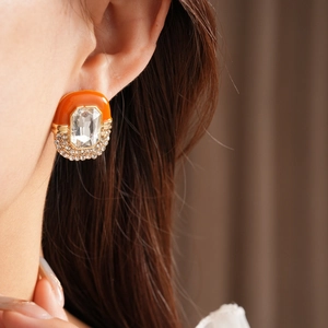 Detailed close-up of vintage oval enamel earrings with crystals on woman's ear