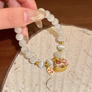 Dettaglio bracciale di perline con pietre occhio di gatto bianche e ciondolo a cavallo