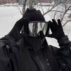 Detail of silver reflective ski goggles and black outdoor jacket on snowy mountain scene