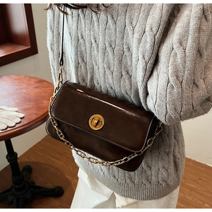 Detail of dark brown vintage faux leather shoulder bag with golden chain and metal buckle