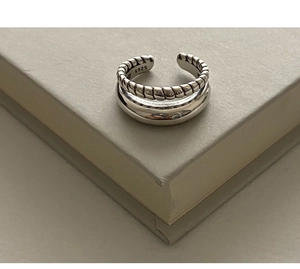 Close-up of S925 sterling silver double-layer twist ring with polished finish on a book