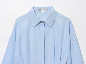 Detail of light blue shirt collar with unique metal button and size label