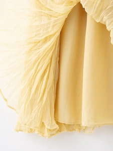 Close-up of lightweight pleated pale yellow chiffon fabric with soft vertical texture