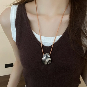Close-up of a vintage silver shell pendant necklace with a textured vertical pattern