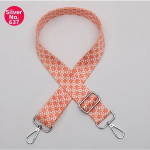 Macro view of adjustable orange strap with white floral pattern and silver metal hooks
