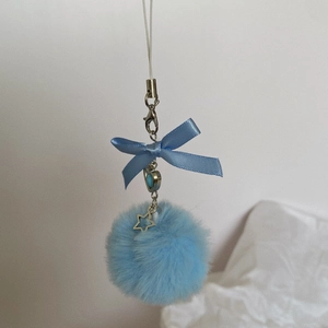 Detail of blue plush pompom charm with silk bow and hollow star metal pendant
