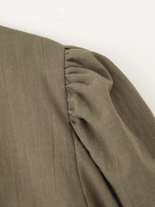 Detailed close-up of army green cotton linen shirt shoulder with pleated puff sleeve texture
