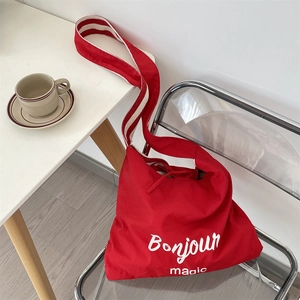 Détail du sac cabas en toile rouge avec imprimé Bonjour magic et bandoulière rayée