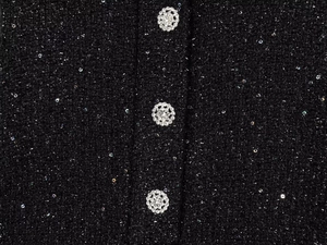 Detail von schwarzem Tweed-Stoff mit Pailletten und silbernen Strass-Blumenknöpfen