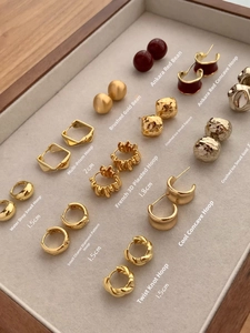 Detailed display of assorted gold-plated geometric hoop and stud earrings in a jewelry tray