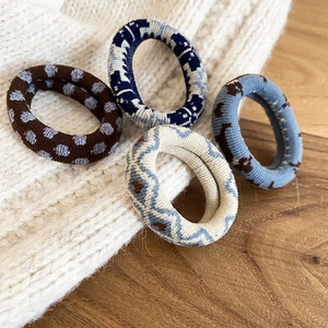 Quatre chouchous tricotés aux motifs variés posés sur un pull blanc pour un style rétro