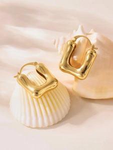 Detail of 18k gold plated U-shaped geometric earrings on a seashell and silk background