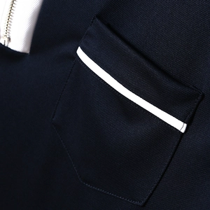 Macro shot of navy polo shirt featuring silver zipper and white piped pocket detail