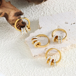 Elegante goldene Creolen mit Zirkonia-besetzten Ringen auf natürlichen Dekorationen