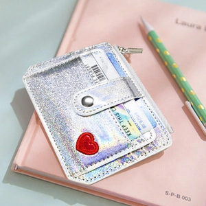 Detail of silver holographic PU card holder with red heart embroidery on pink notebook