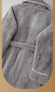 Detail of plush charcoal grey bathrobe featuring thick fleece fabric and white contrast piping