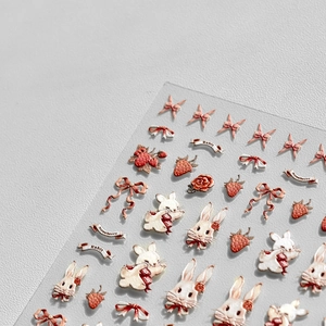 Macro shot of 5D embossed nail stickers with cute white rabbits and red strawberries