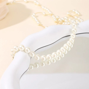 Close-up of elegant white pearl bracelet on a mirrored white wave stand