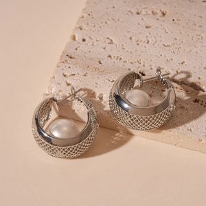 Close-up of wide C-shaped mesh metal earrings with integrated white pearl inlay