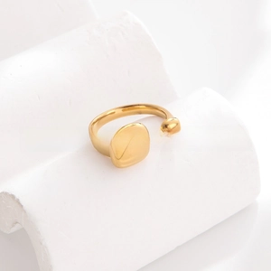 Macro detail of gold-plated geometric ring with square and sphere accents on stone
